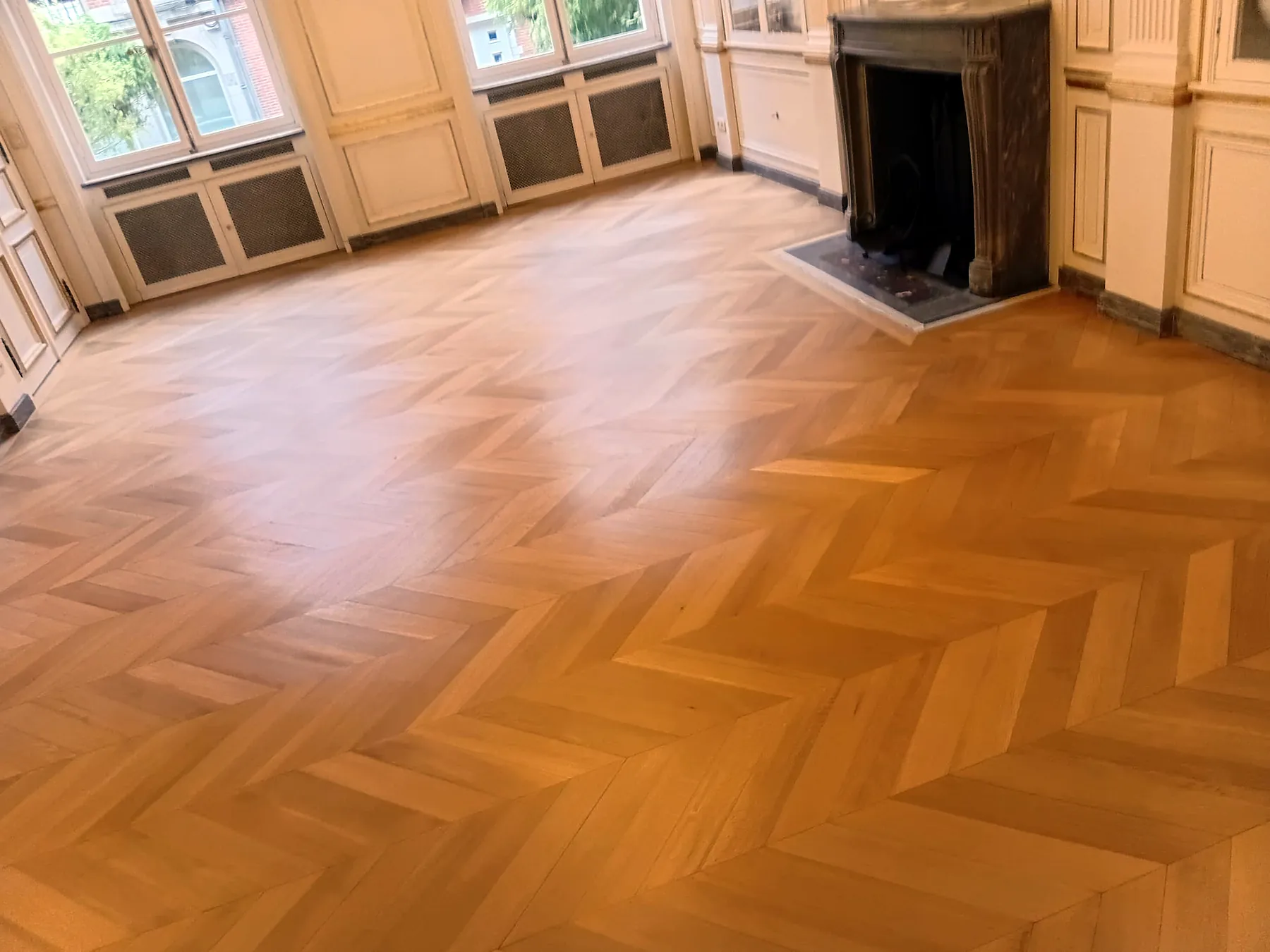 Parquet à chevrons posé avec soin autour d’une cheminée en marbre