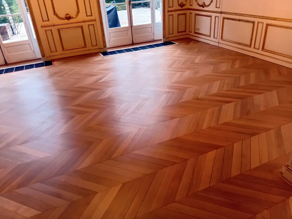 Parquet à chevrons rénové dans un salon à boiseries dorées