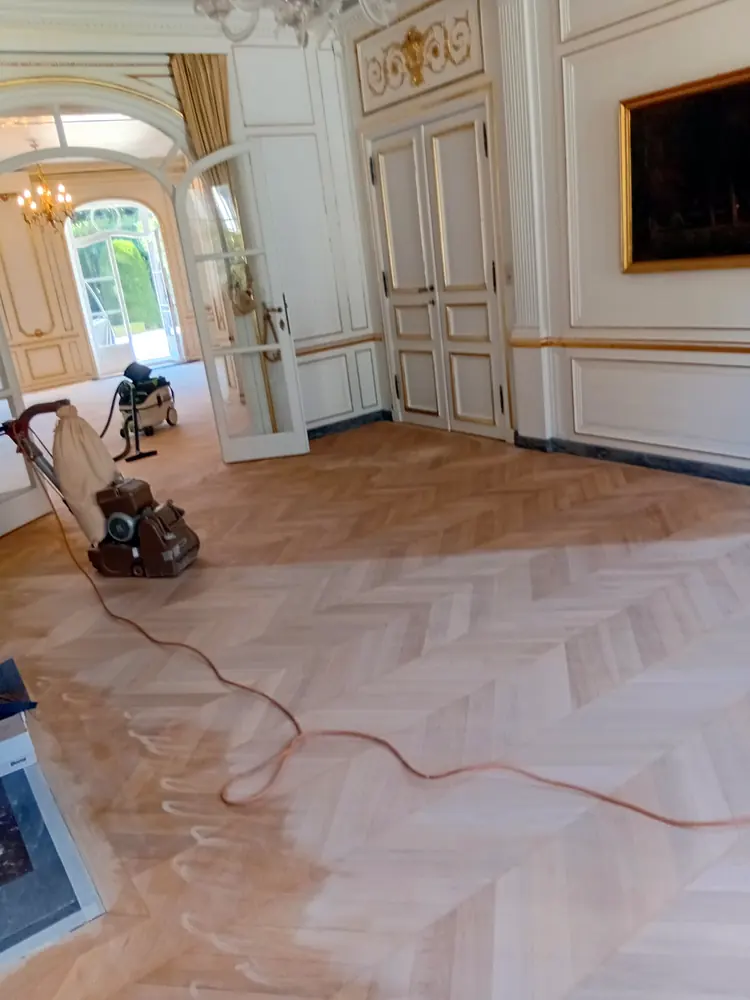 Frontière entre bois poncé et bois non poncé sur un parquet à chevrons