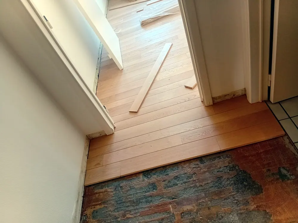 Pose de lames de parquet en chêne au niveau d’un seuil de porte