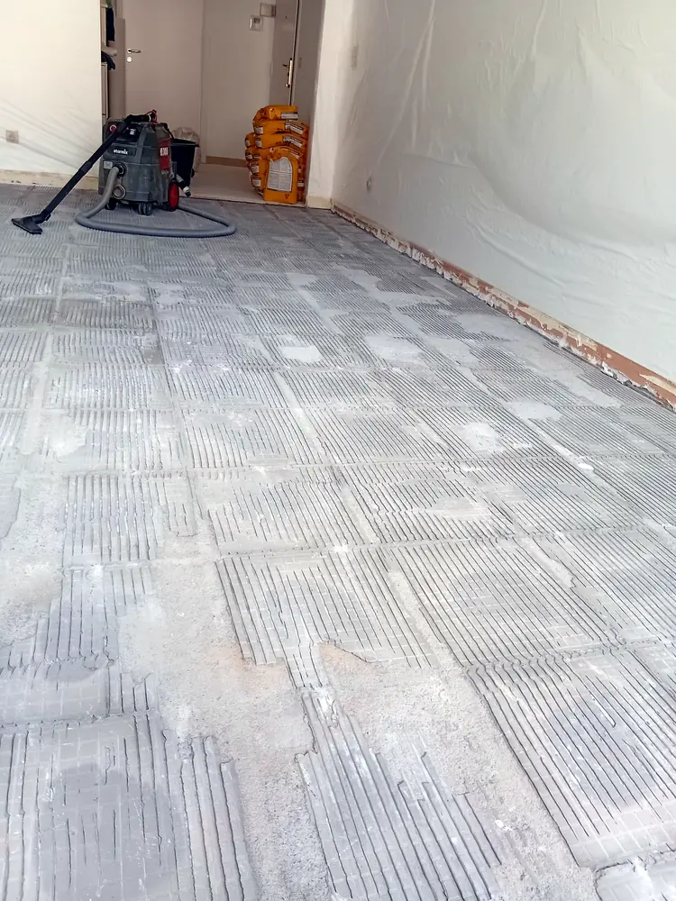 Support nettoyé avant la pose d’un parquet, aspirateur de chantier au fond