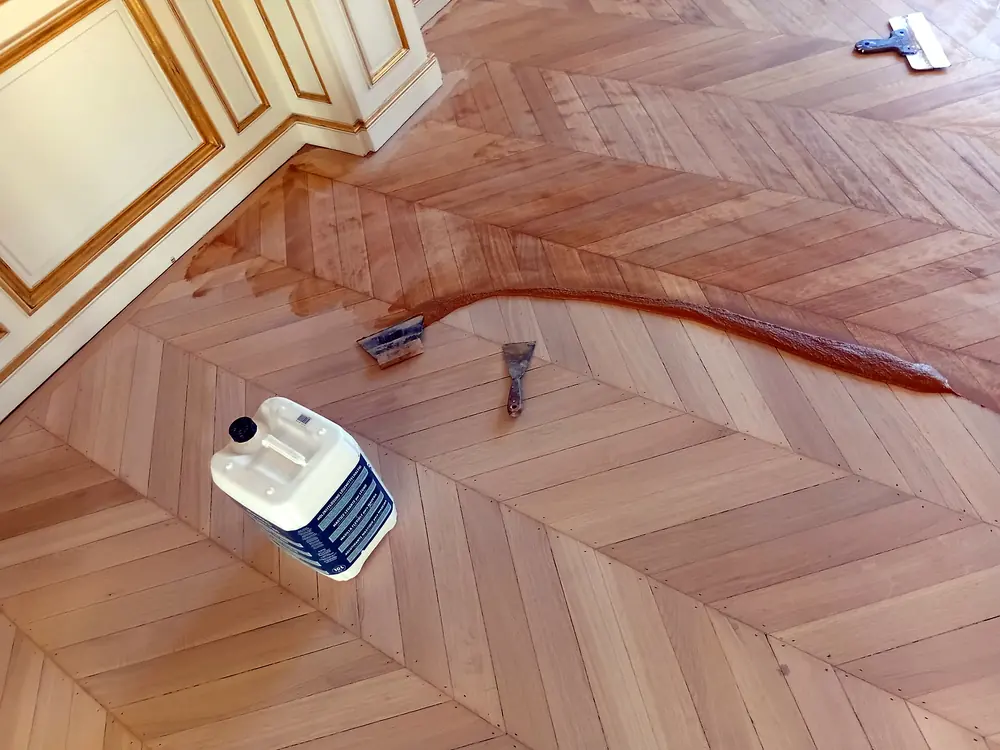Application de mastic à bois sur un parquet à chevrons