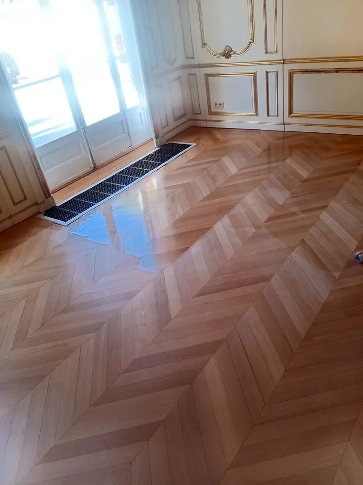 Parquet à chevrons fraîchement vitrifié près d’une grille de ventilation