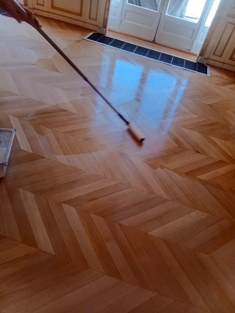 Application de vernis au rouleau sur un parquet à chevrons